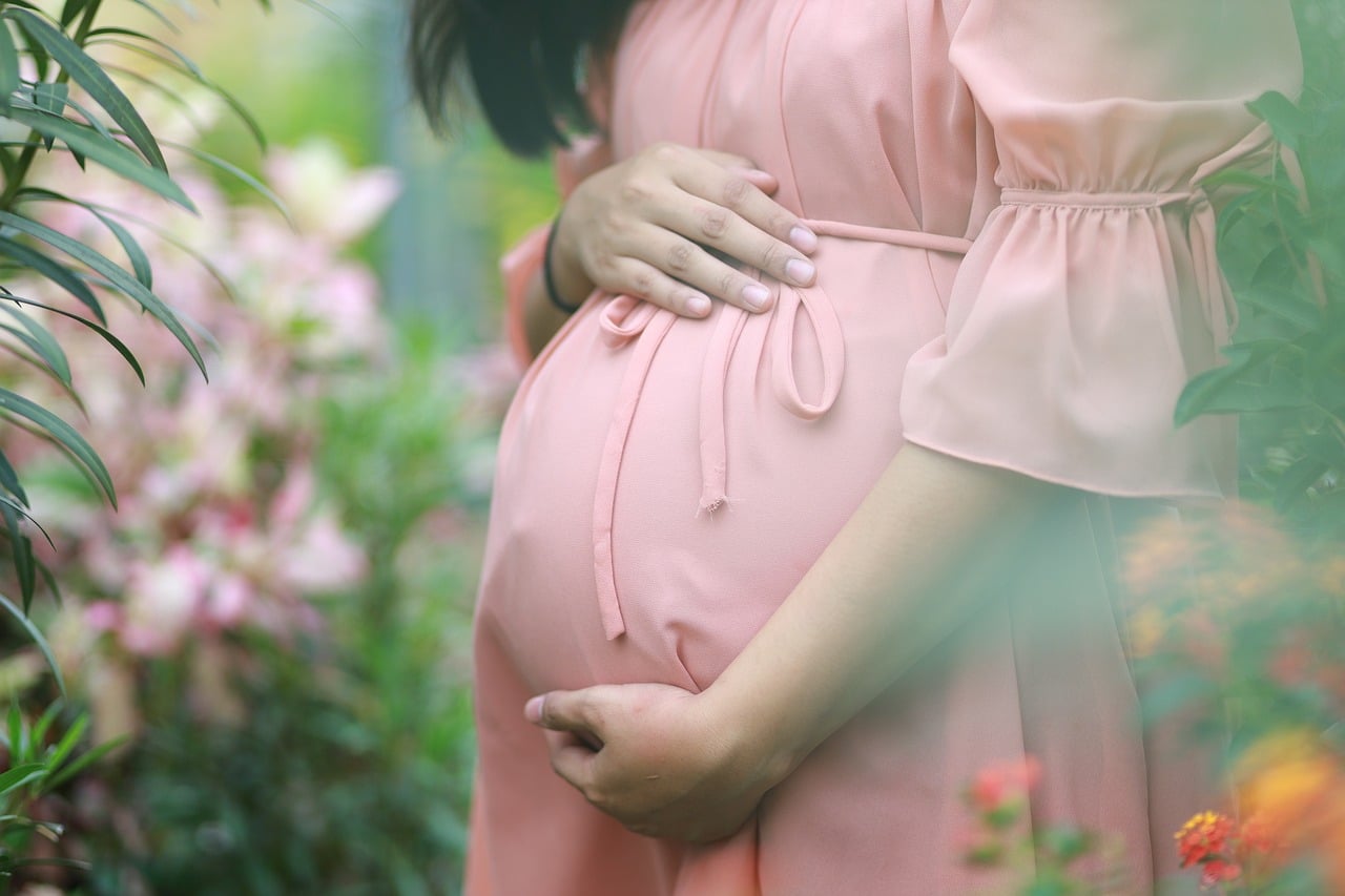 pregnant-woman-in-pink-dress-holding-her-belly