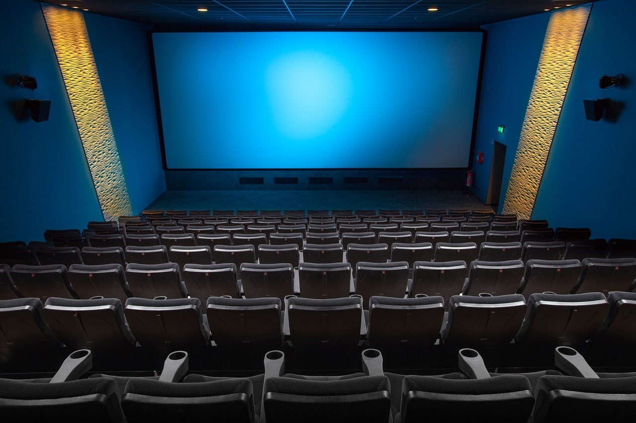 shot-of-movie-theater-from-behind-black-chairs-facing-blue-screen