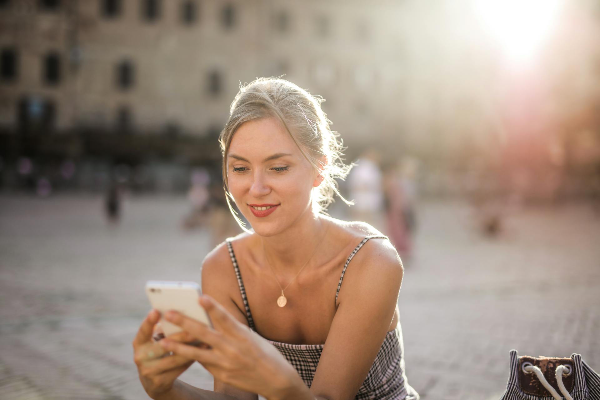 woman-in-white-and-black-stripe-spaghetti-strap-top-smiling-happily-at-phone