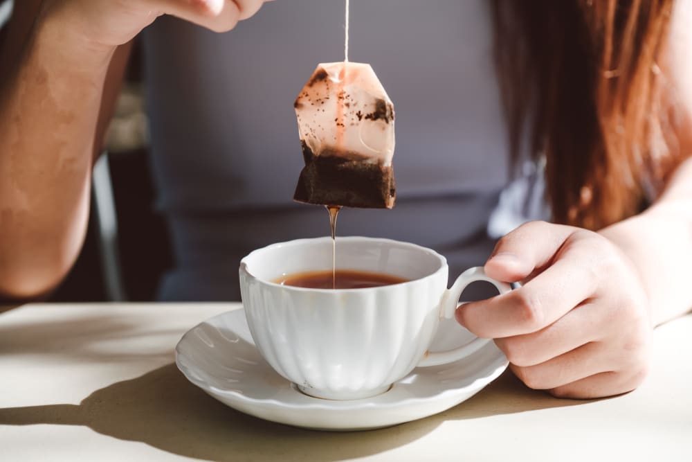 woman soaking a tea bag in hot water