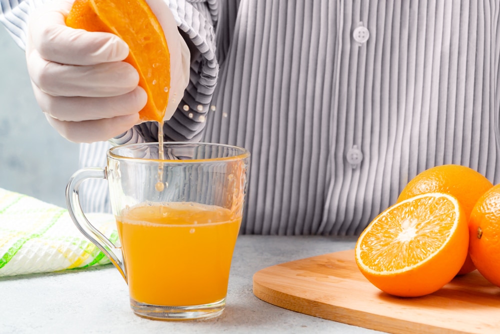 woman squeezing orange juice into a glass