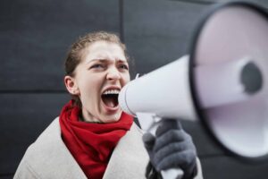 woman with red scarf shouting through megaphone