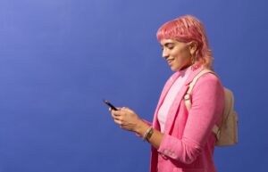 person with pink hair and pink suit texting on their phone