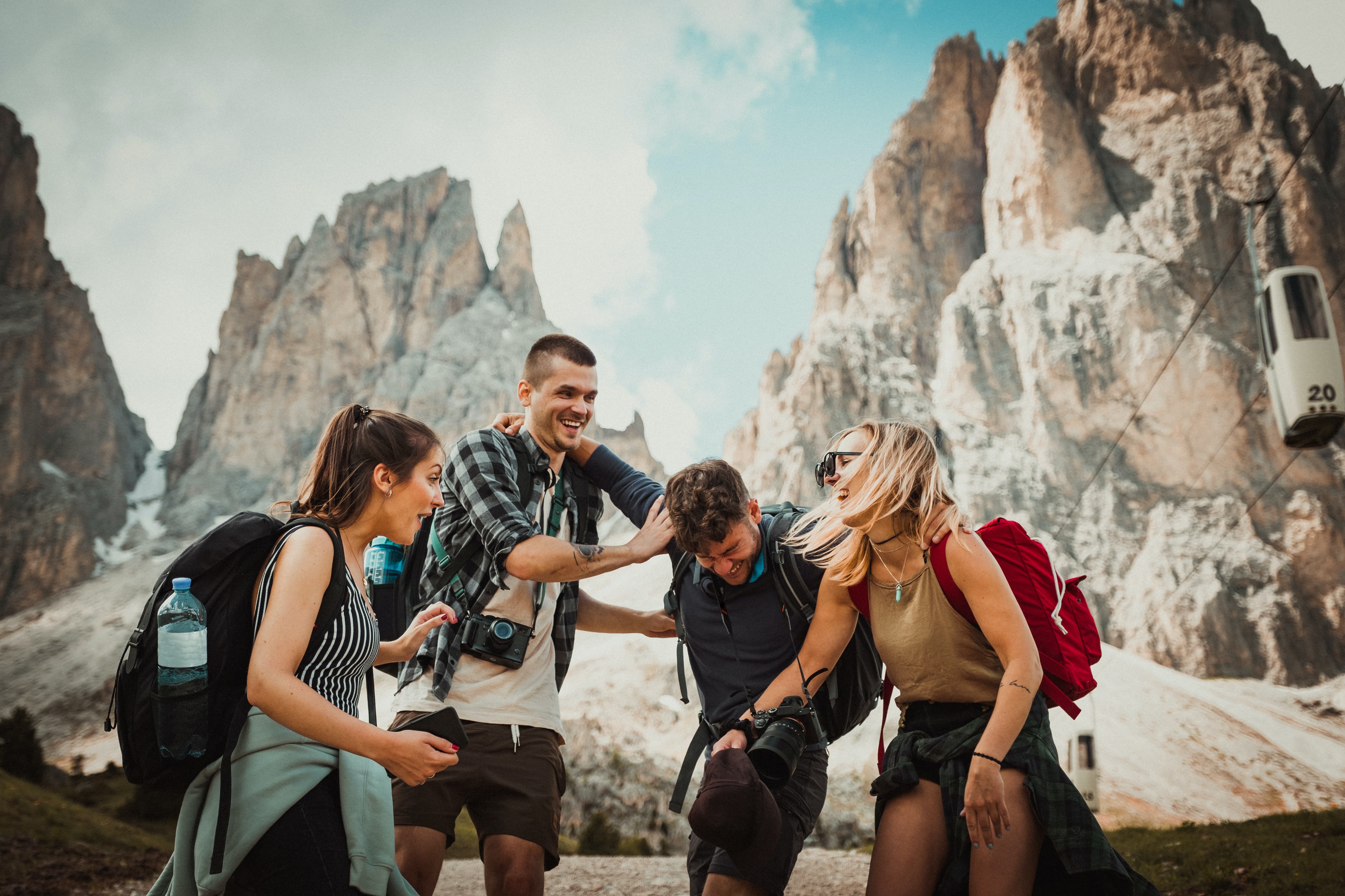 A group of friends hiking in the French Alps stop to tell a joke and laugh