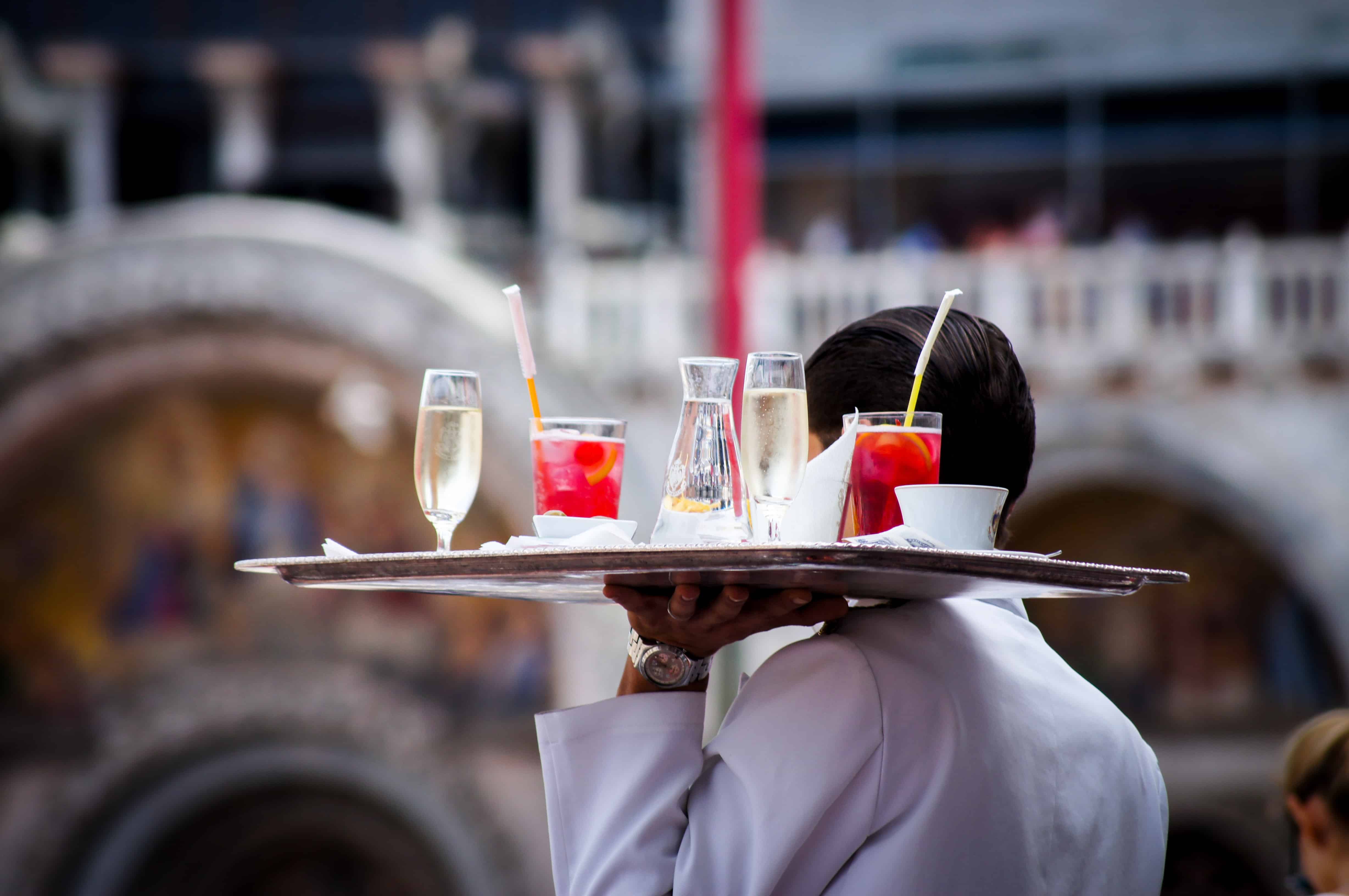 Waiter carrying a tray a drinks over his shoulder.