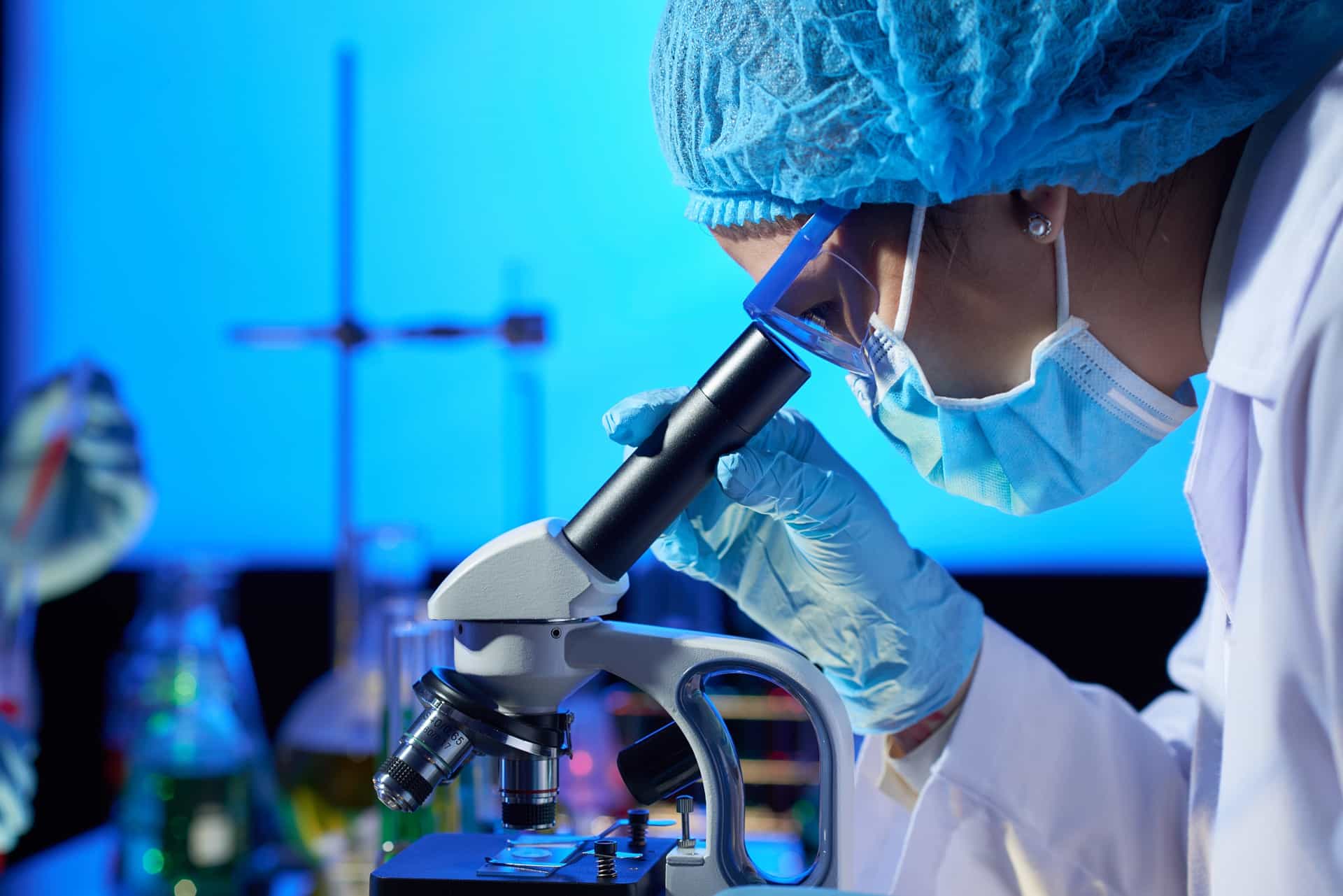 A lab worker looks into a microscope.