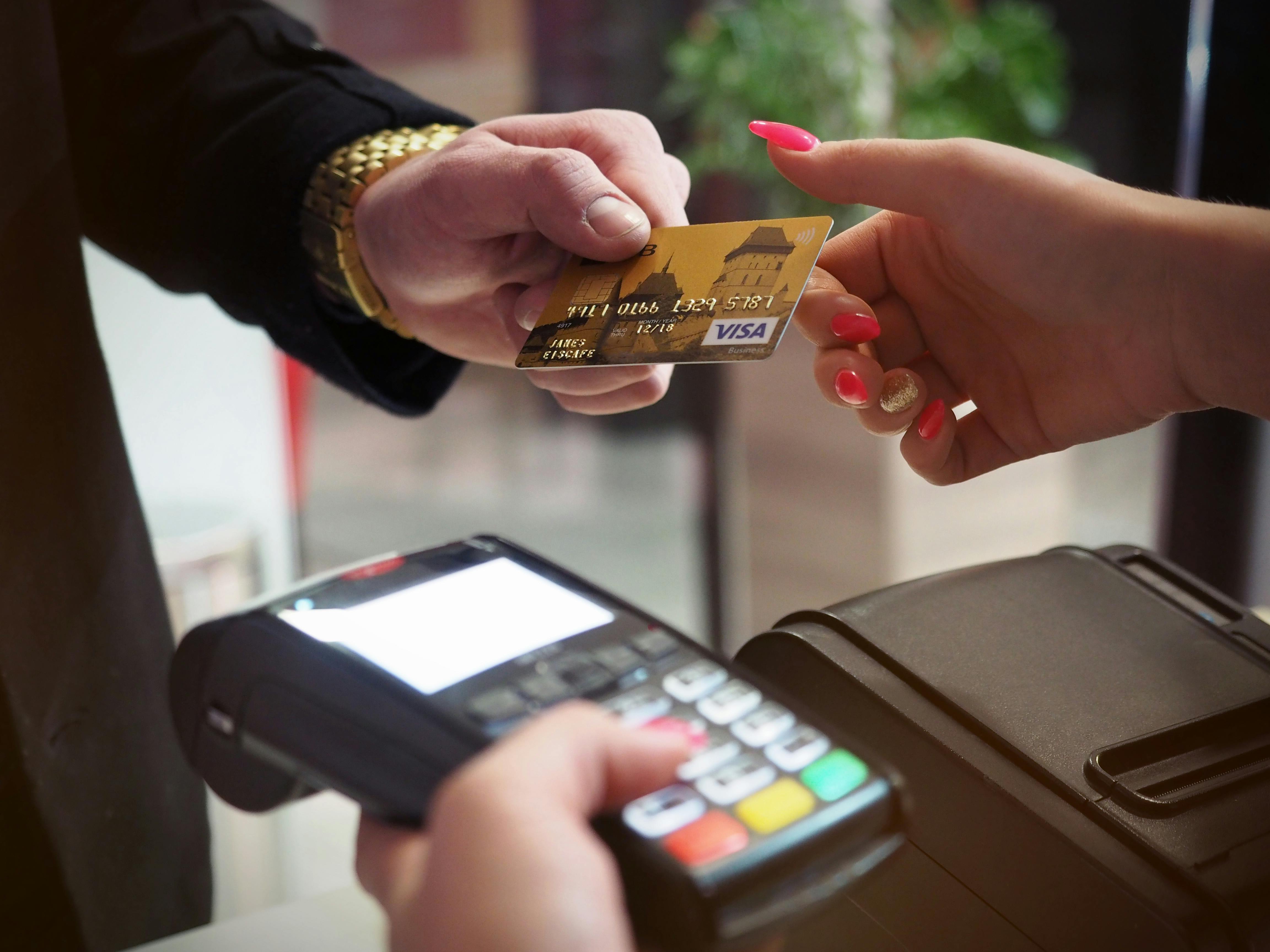 person-giving-credit-card-to-cashier-holding-pdq-machine