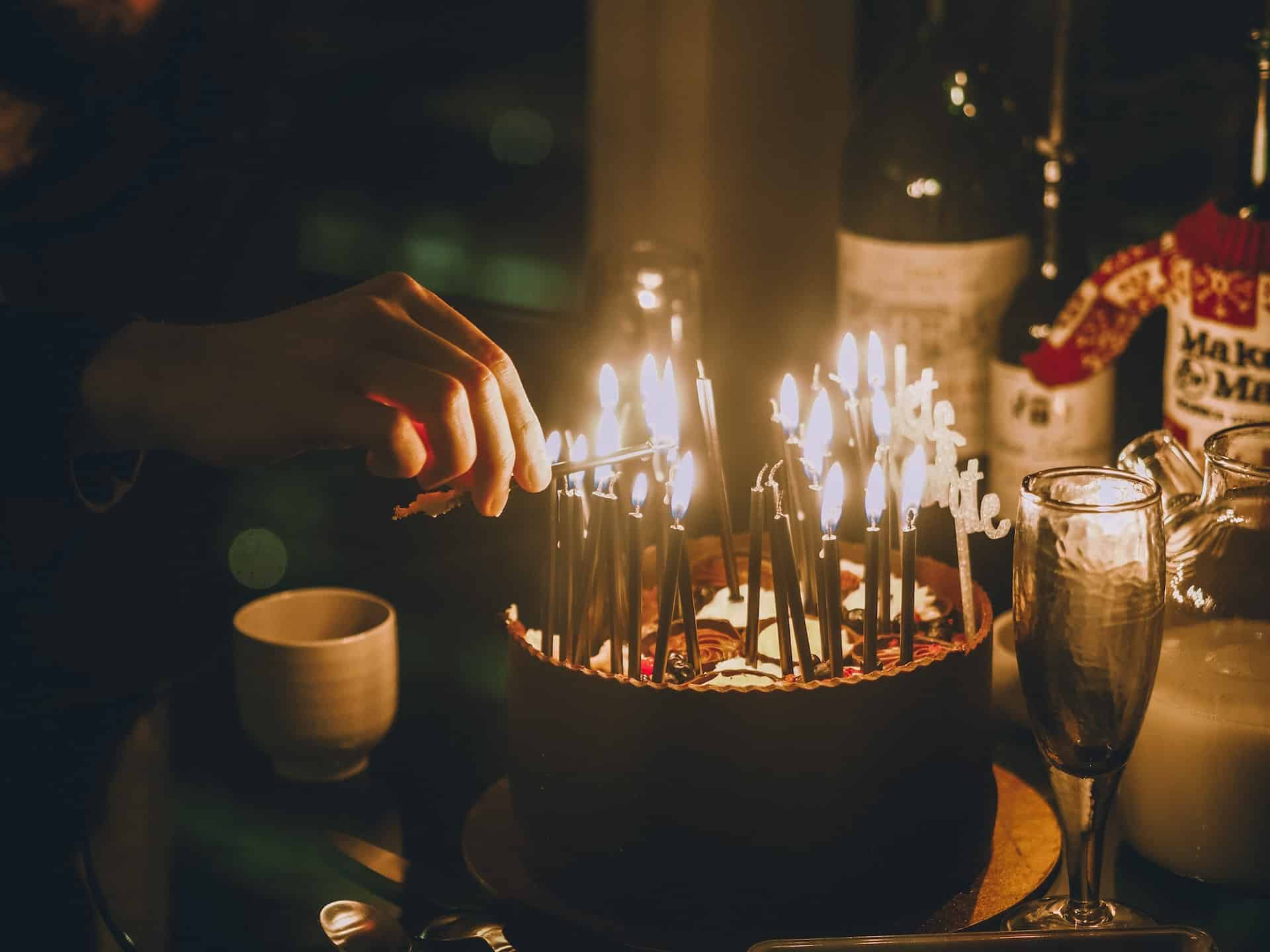 person lighting birthday candles on a cake