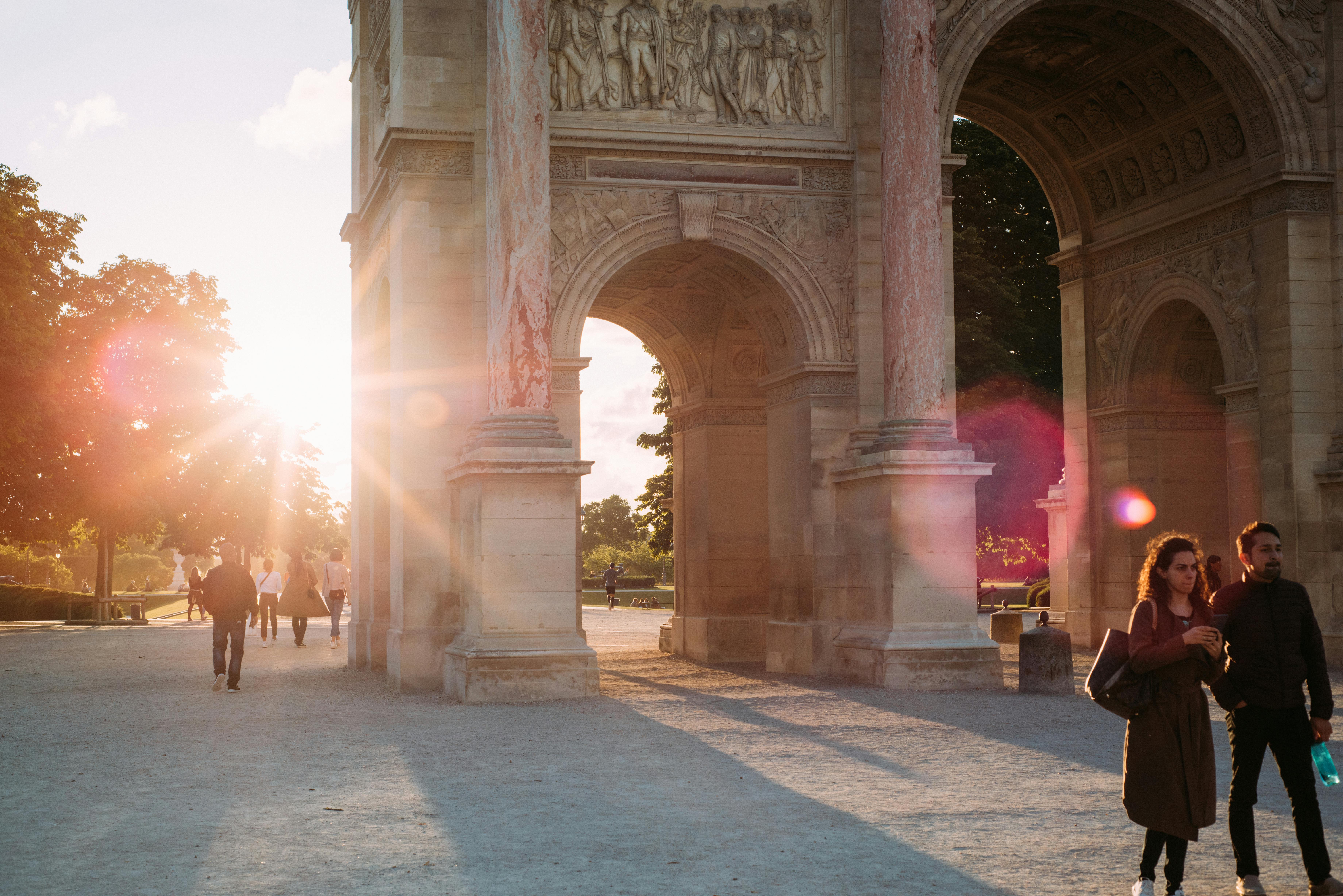 A couple walks by a beautiful arch in Paris