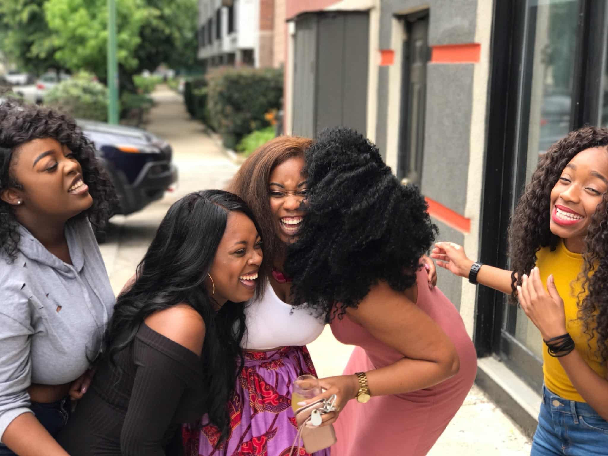 A group of female friends stops and laughs on the street