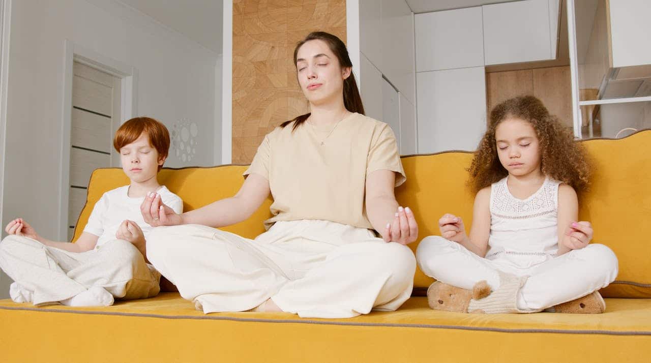 An adult and two kids practising meditation