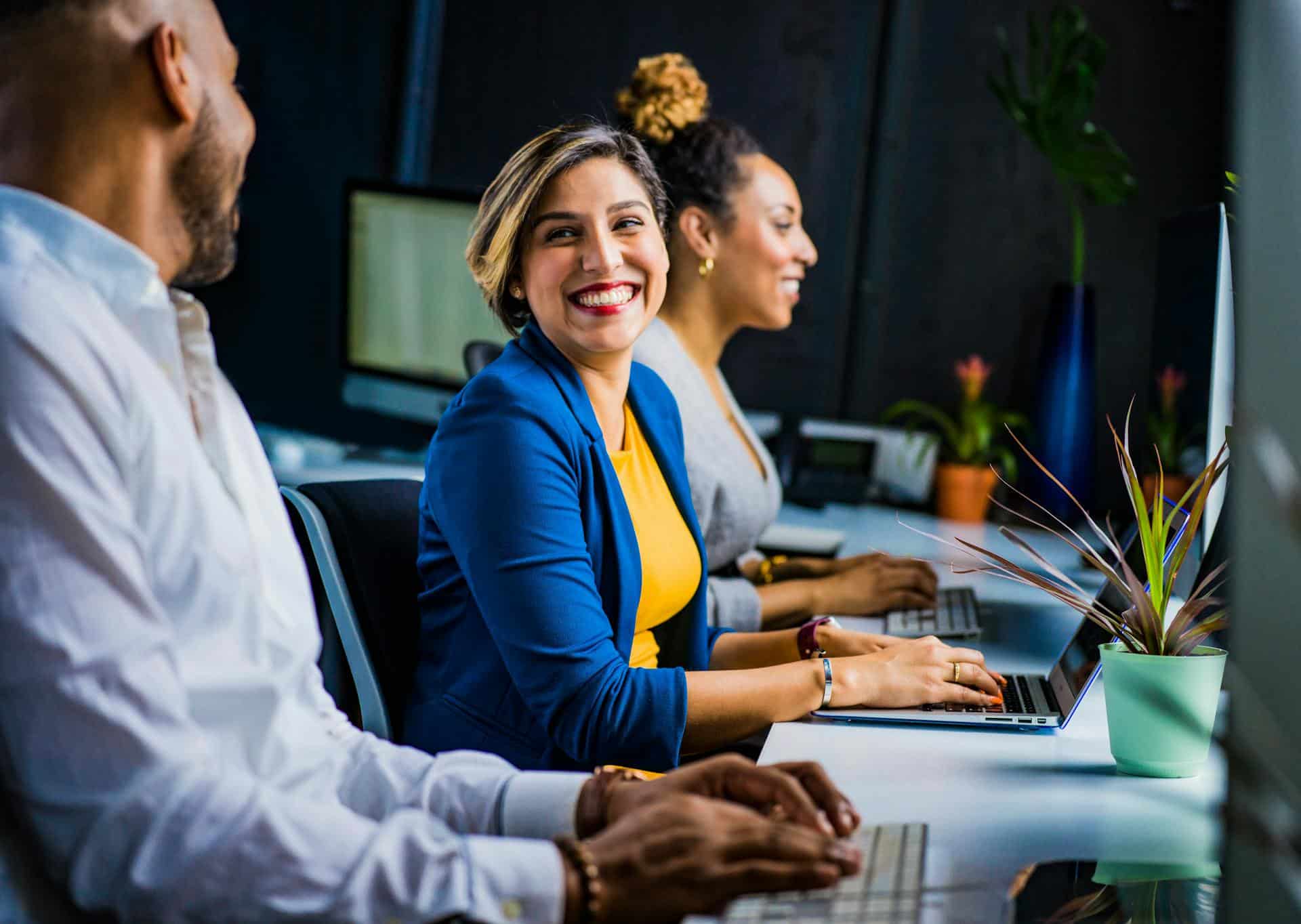 woman-in-blue-suit-jacket-smiling-at-coworker-in-office