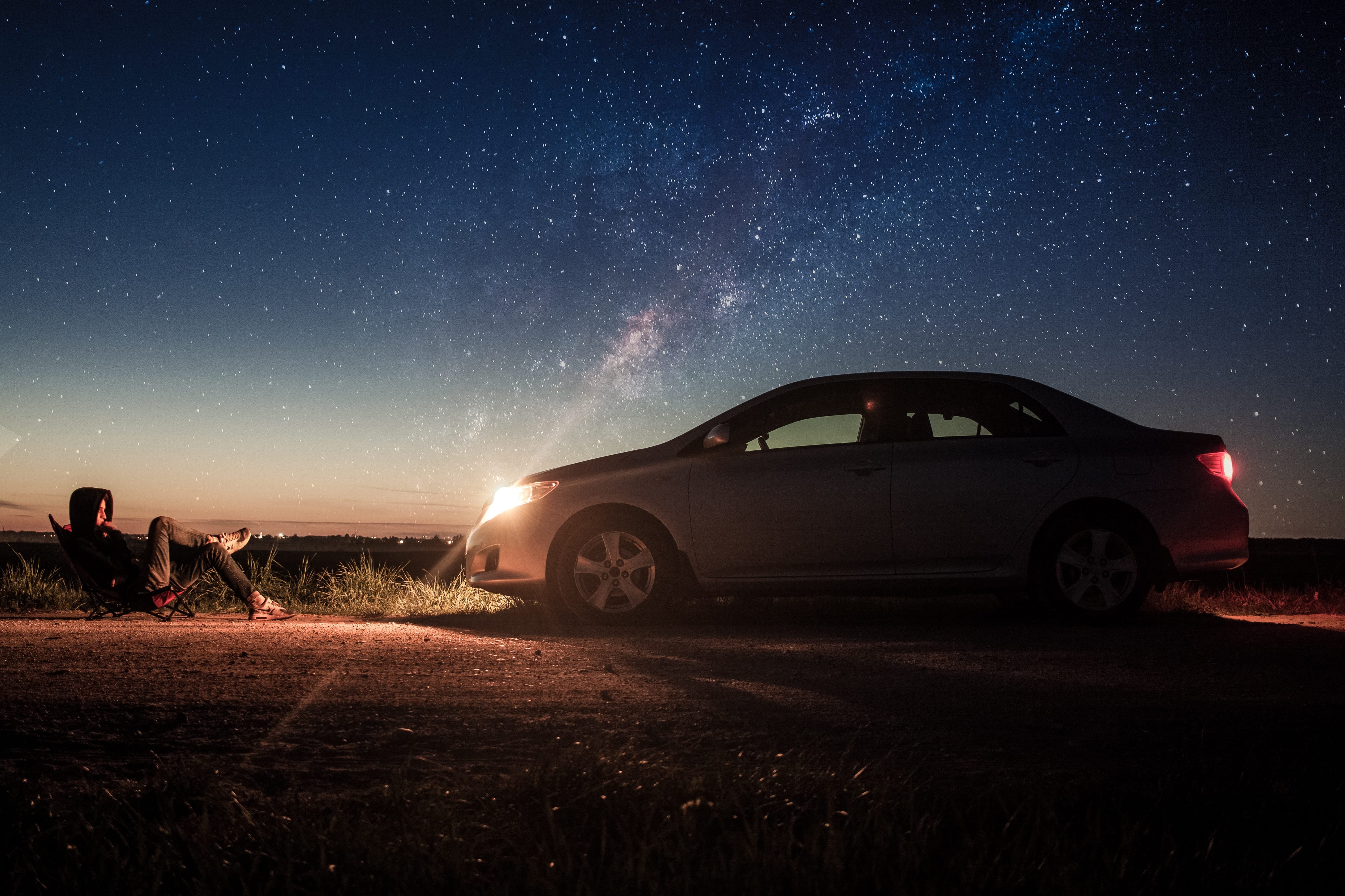 A man sitting in the light of his car headlights