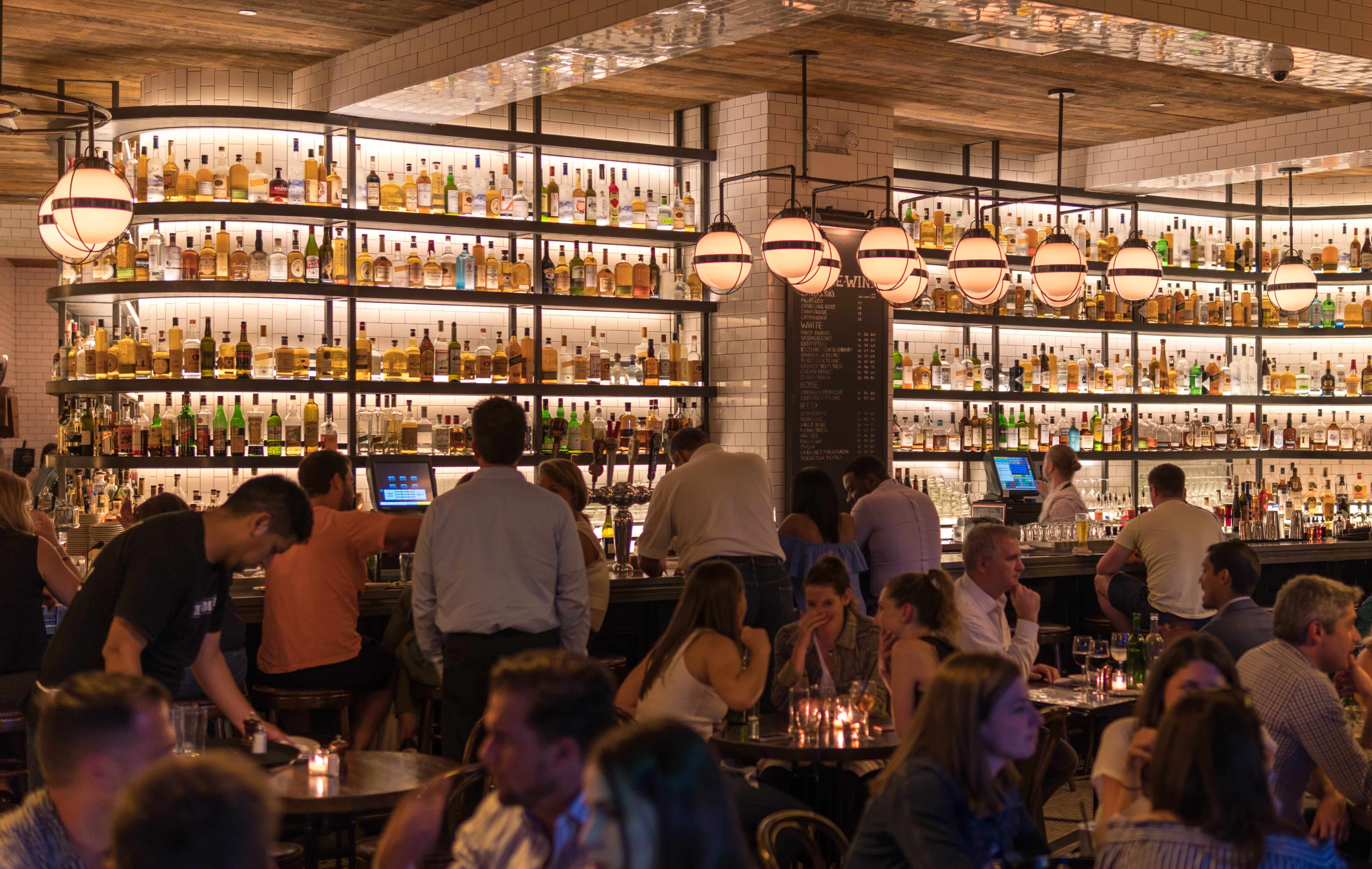 Diners sitting at a bar in a large busy restaurant