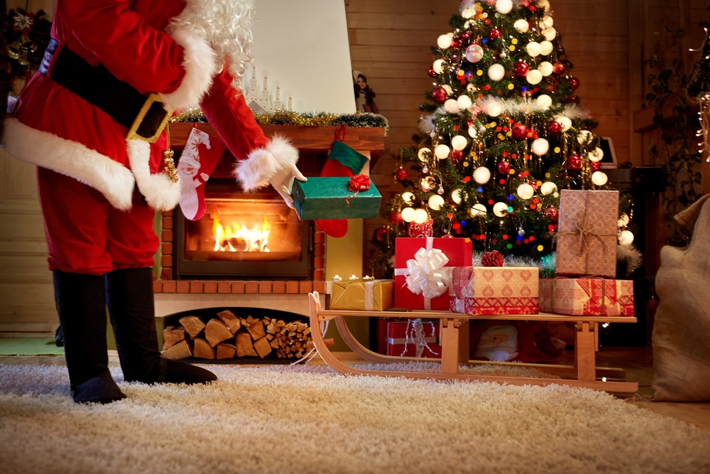 santa claus putting gifts at christmas tree