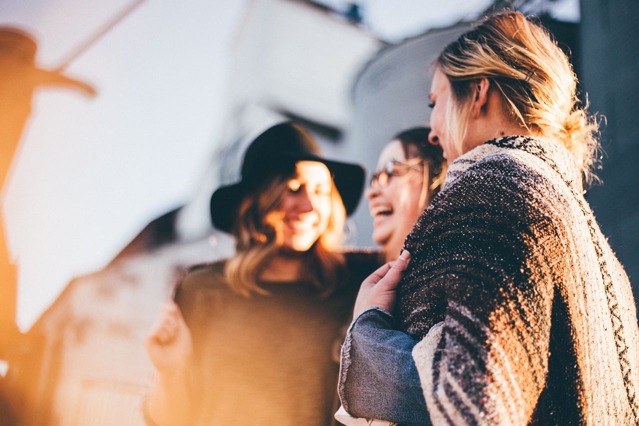 three women standing together laughing