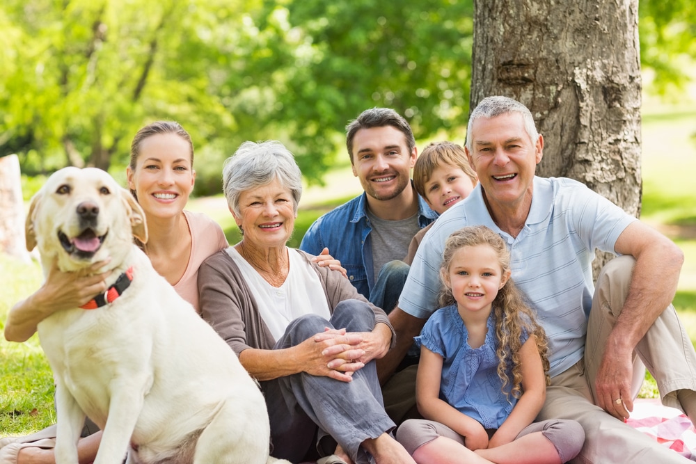 family-sitting-in-park-with-dog