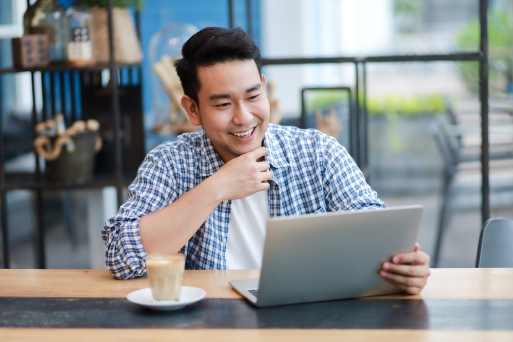 guy using his laptop at a cafe and laughing