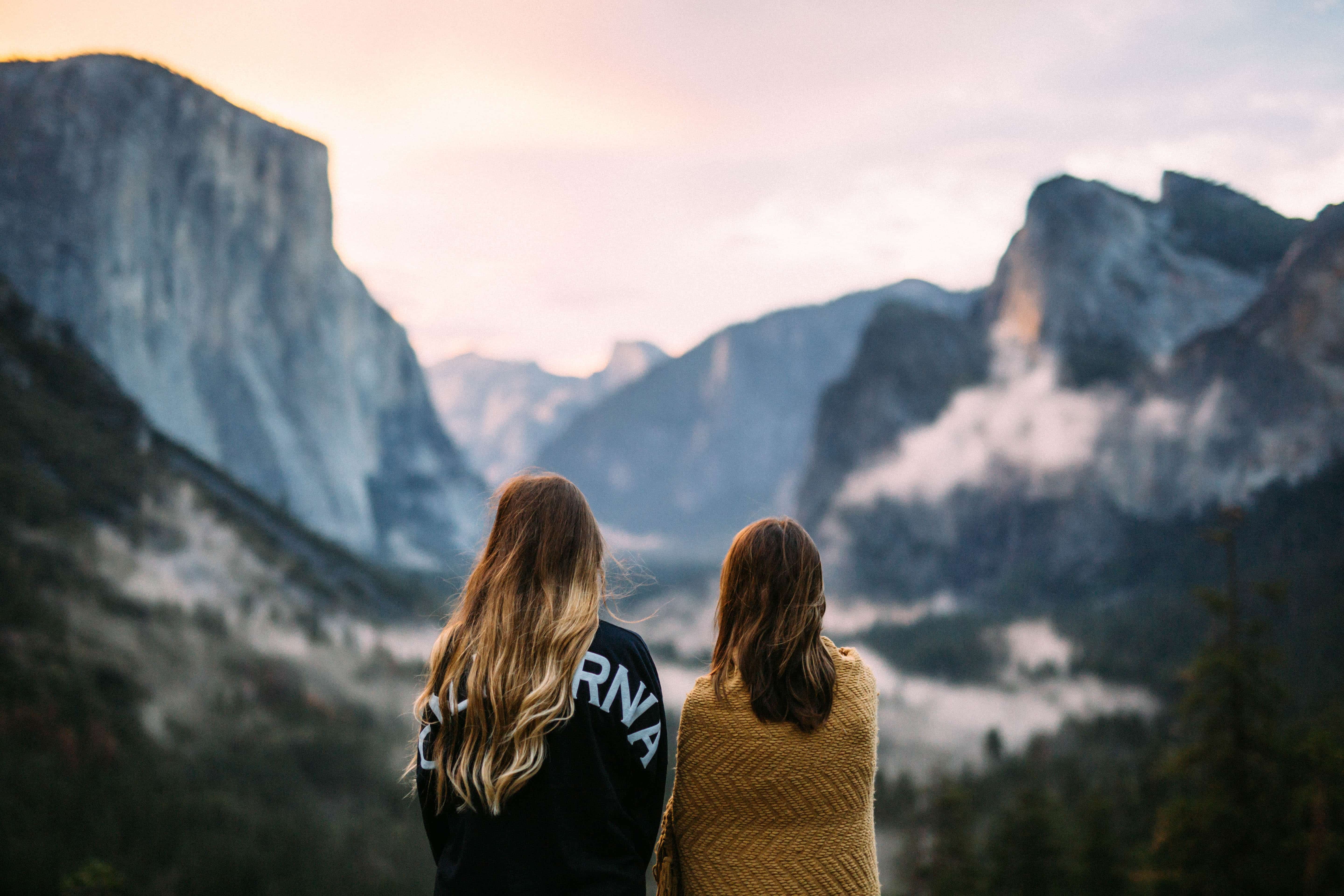 Two people facing out towards the mountains