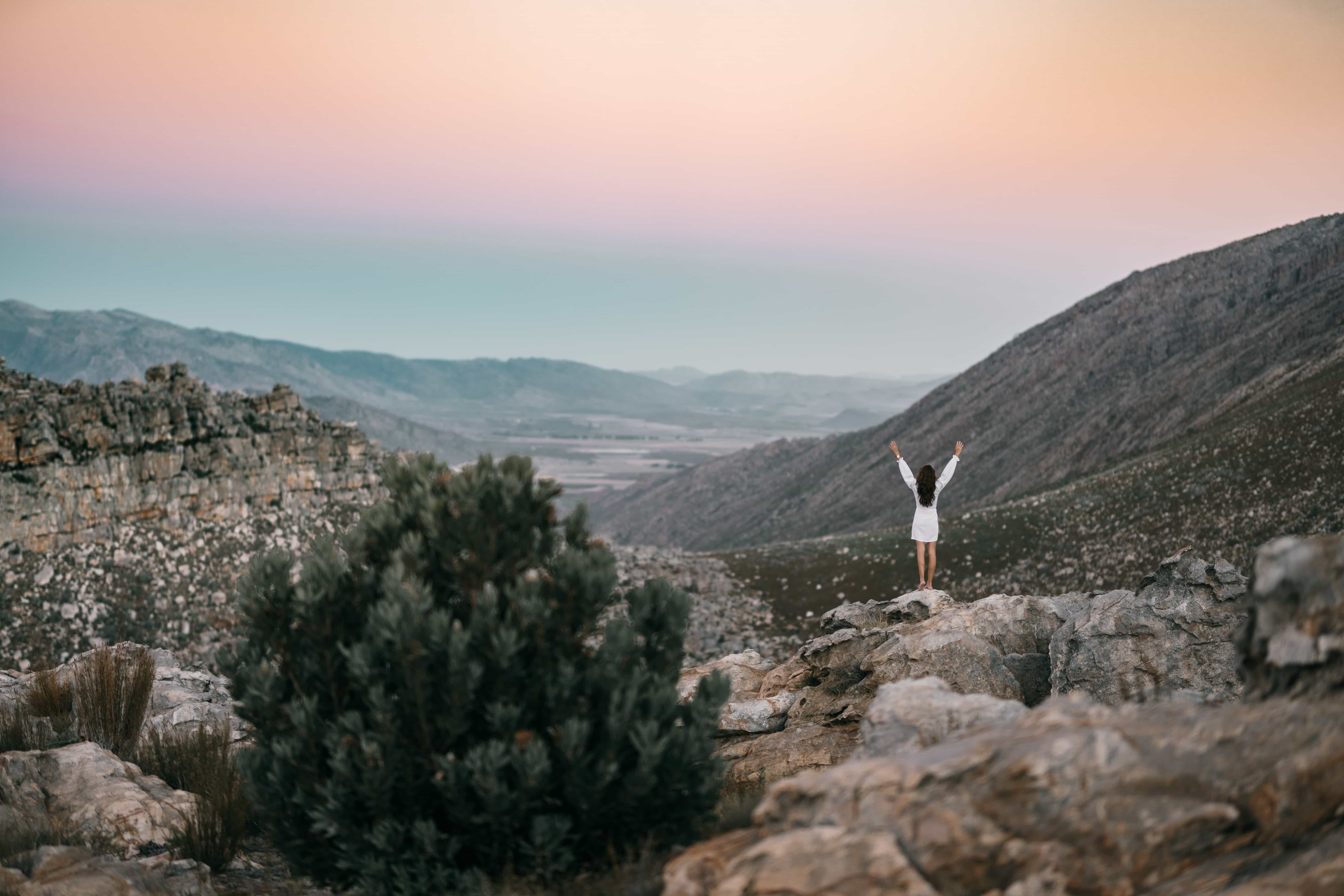 Person standing in nature pointing arms towards the sky