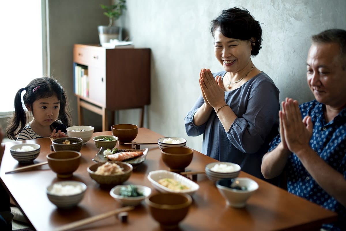 asian-family-sitting-together-at-dinner-table-with-side-dishes