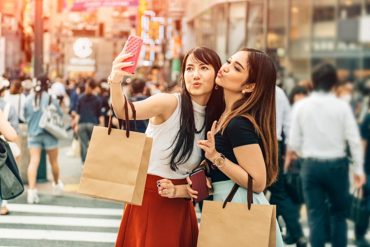 two japanese girls taking a selfie after shopping