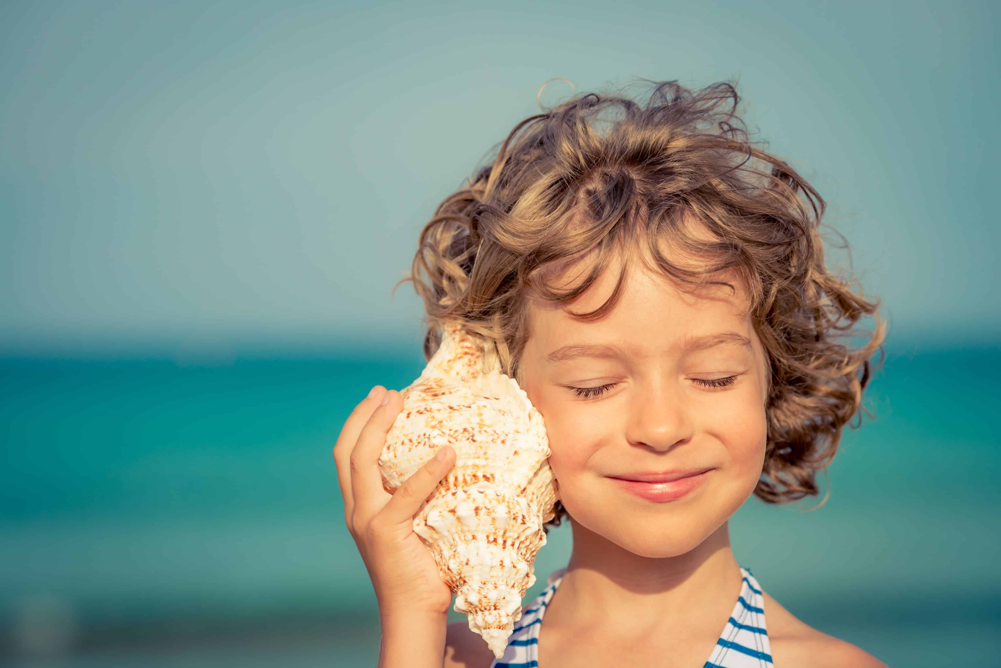 Child listening to a sea shell