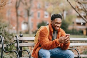 man smiling looking at phone in park