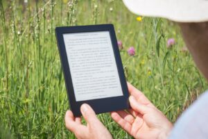 person holding an ereader in grass