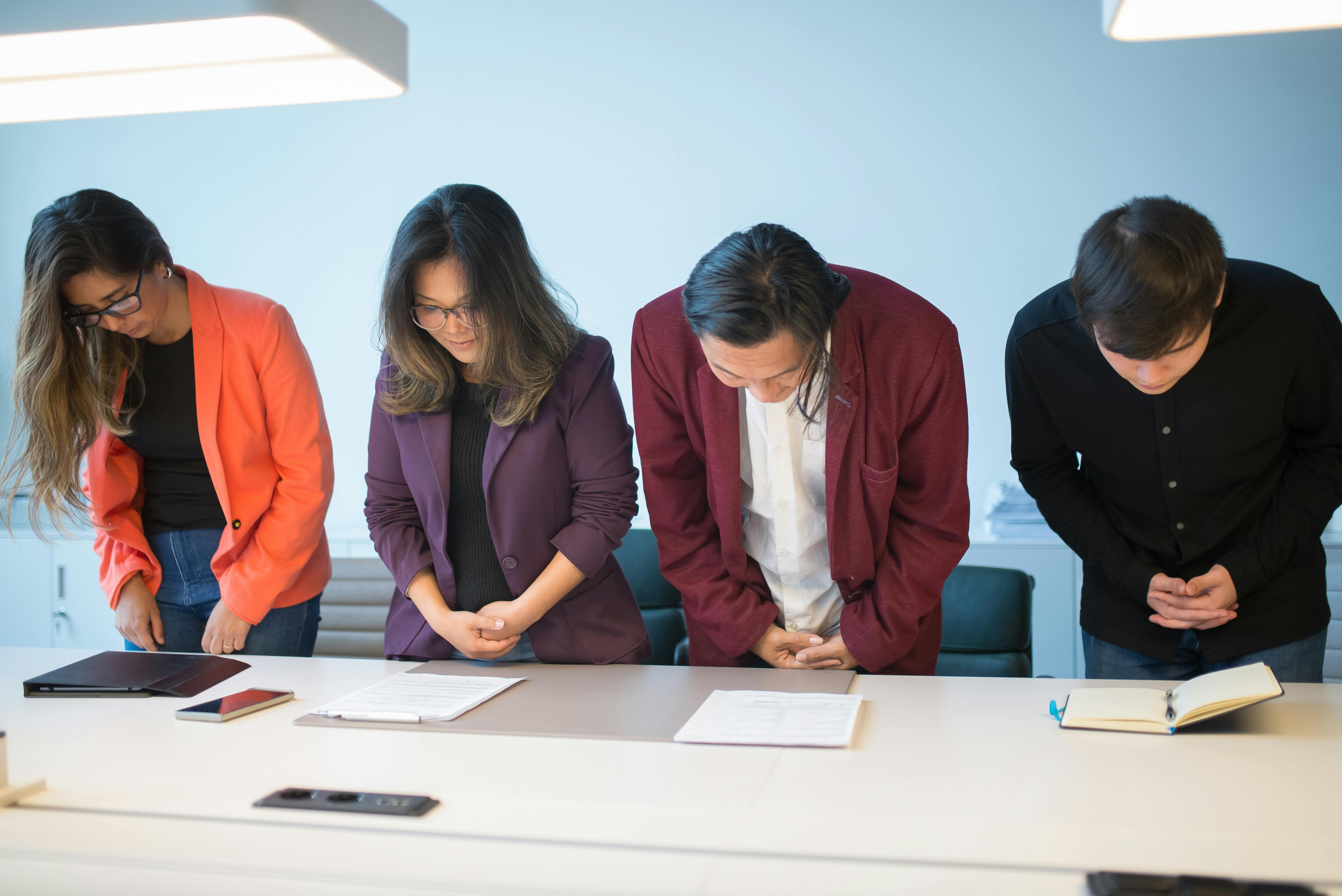 Four colleagues bowing at the end of a business meeting